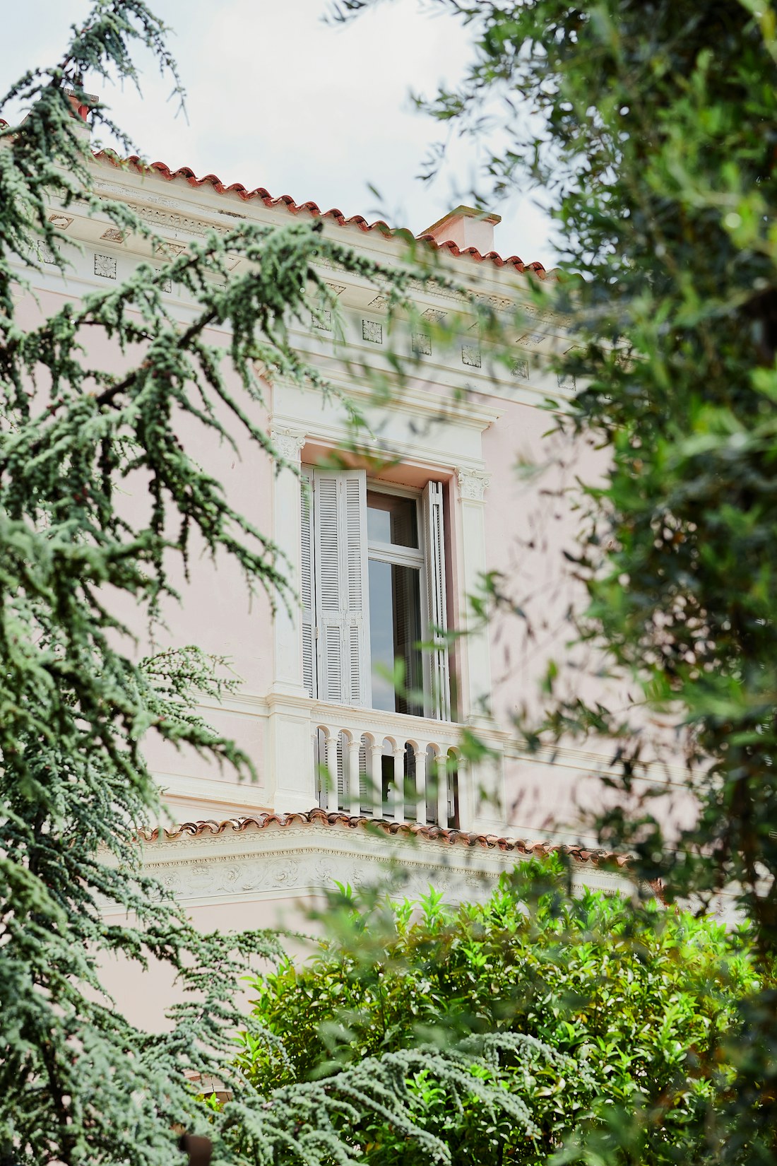 Façade rose à fenêtres blanches et balcon